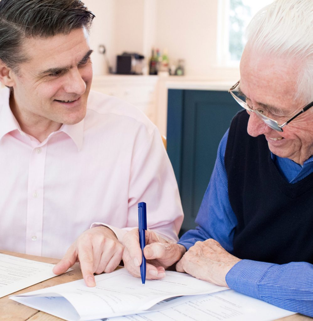 Attorney showing an older man where to sign a power of attorney document